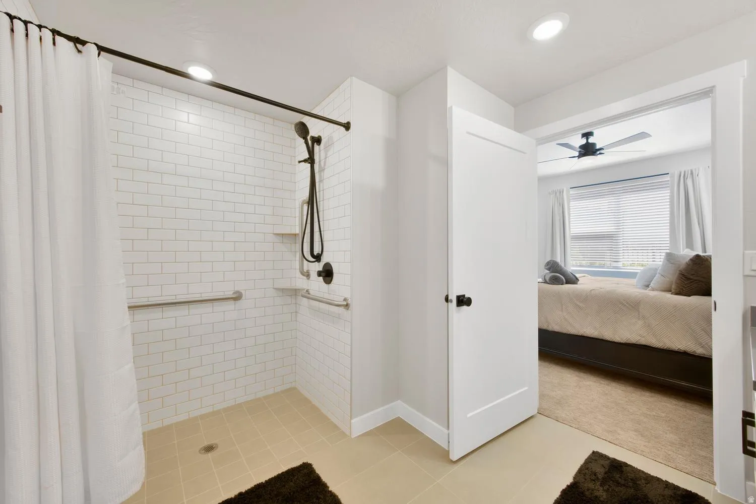 Walk-in shower with white subway tile surround, matte black shower fixtures, and integrated grab bars