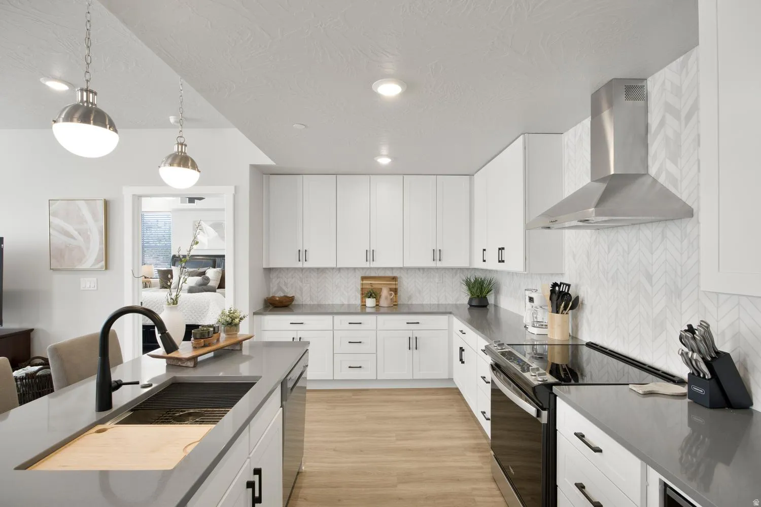 Modern kitchen featuring white cabinetry, dark countertops, and light wood-finish flooring