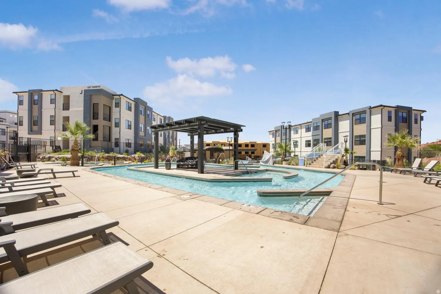 Resort-style pool area featuring a custom pool, integrated lounging areas, and a shaded pergola