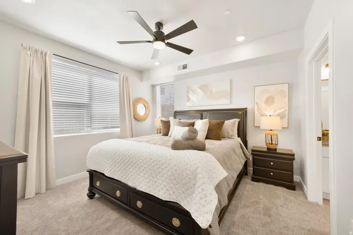 Spacious bedroom featuring plush carpet flooring, a dark wood-finish bed frame, and recessed lighting