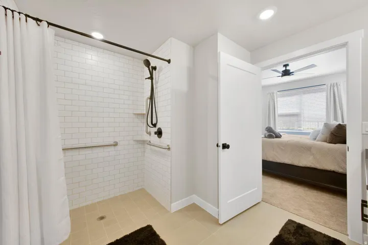 Walk-in shower with white subway tile surround, matte black shower fixtures, and integrated grab bars