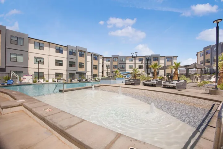 Expansive communal pool area featuring a large swimming pool, a shallow water feature with fountains, and an adjacent lounge area with a shaded gazebo
