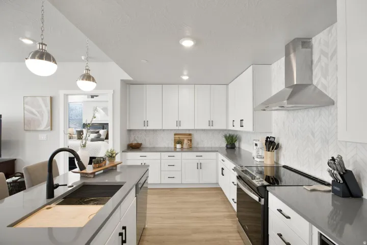 Modern kitchen featuring white cabinetry, dark countertops, and light wood-finish flooring