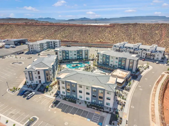 Aerial perspective showcasing a modern multi-building complex with a central swimming pool and surrounding paved parking areas