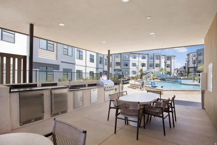 Covered outdoor kitchen featuring stainless steel appliances, an integrated sink, and ample counter space