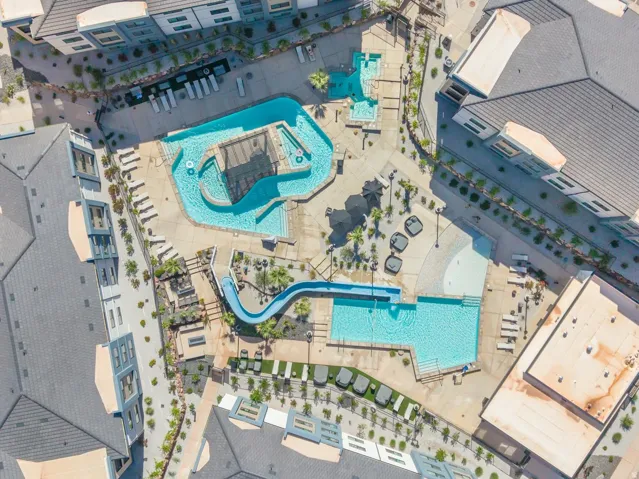 Resort-style aquatic complex featuring multiple pools, a water slide, and a lazy river