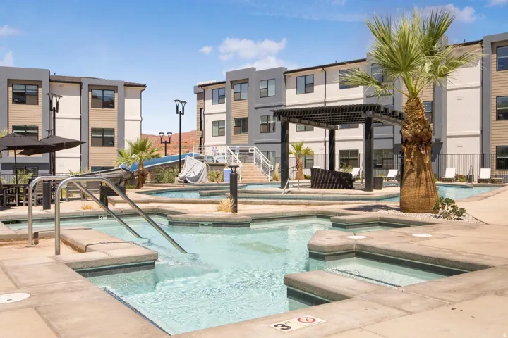 Multi-level pool area featuring integrated spas, a shaded pergola, and surrounding lounge seating