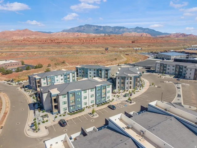 Modern apartment buildings with a neutral and blue facade, surrounded by structured parking areas and landscaping