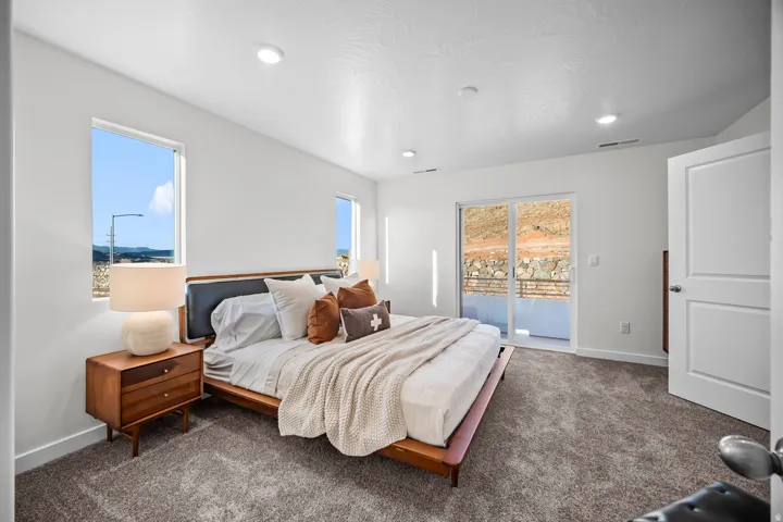 Spacious room featuring broadloom carpeting, two windows, and a sliding glass door leading to a private outdoor space