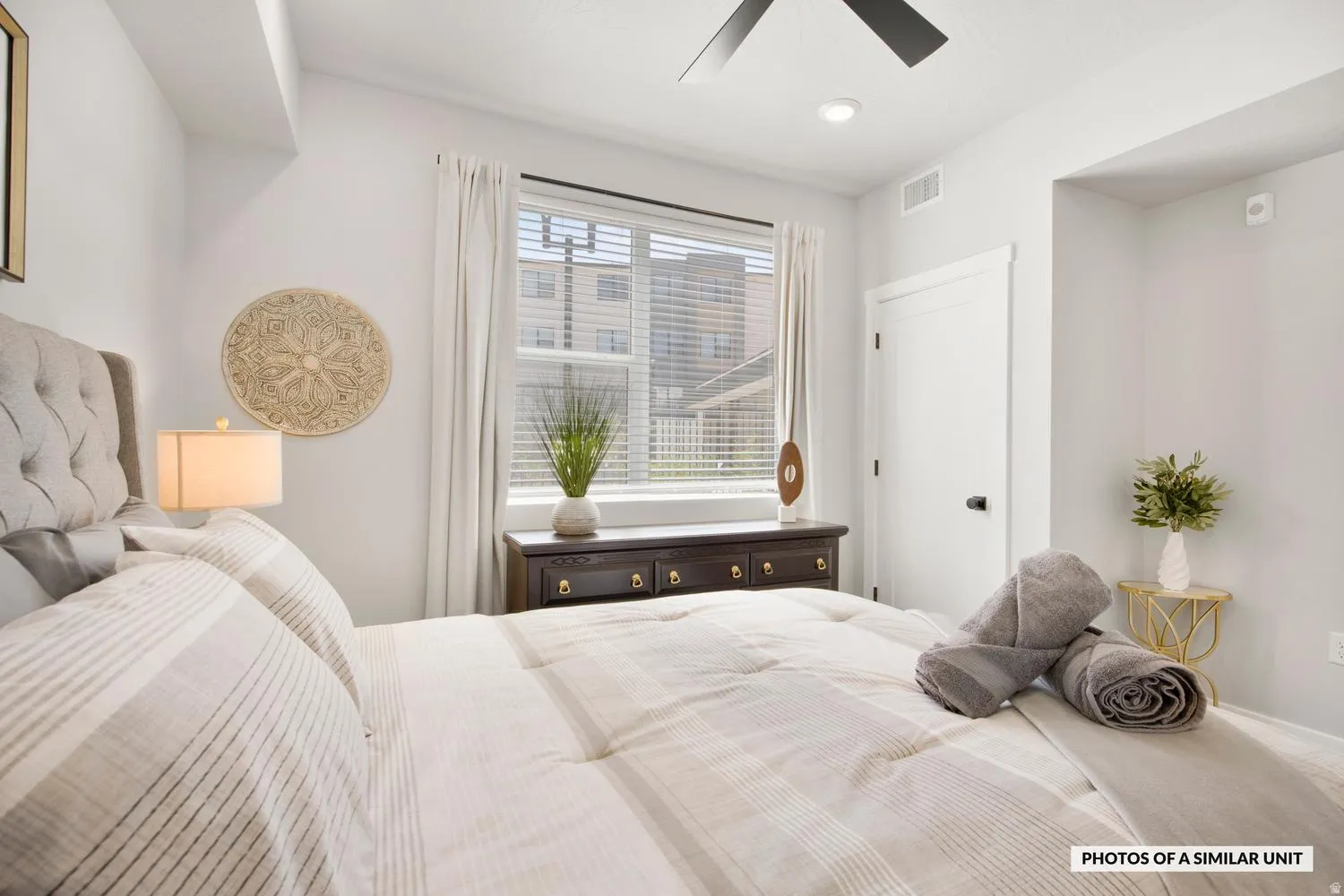 Recessed lighting illuminating a window with blinds, a ceiling fan, and a white interior door with dark hardware
