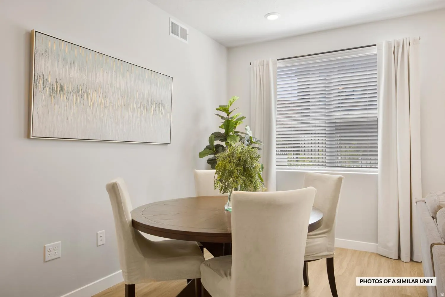 Dining area featuring wood-finish flooring and a window with blinds and drapes