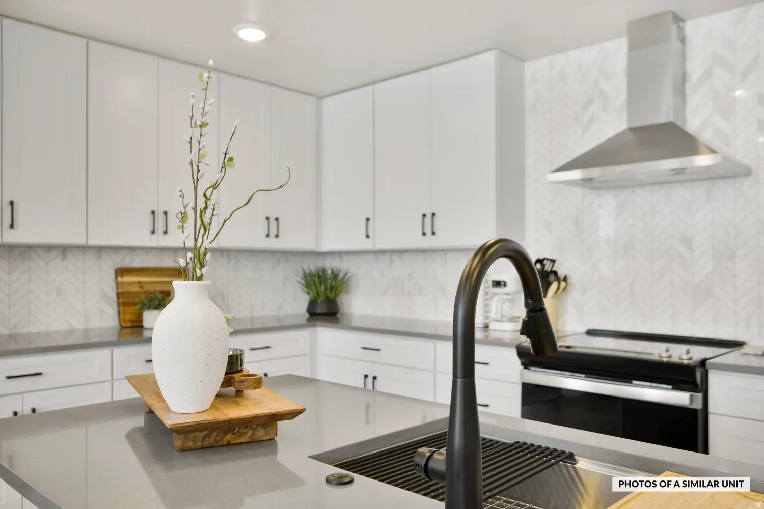 Modern kitchen featuring a matte black gooseneck faucet, integrated sink, and sleek gray countertops