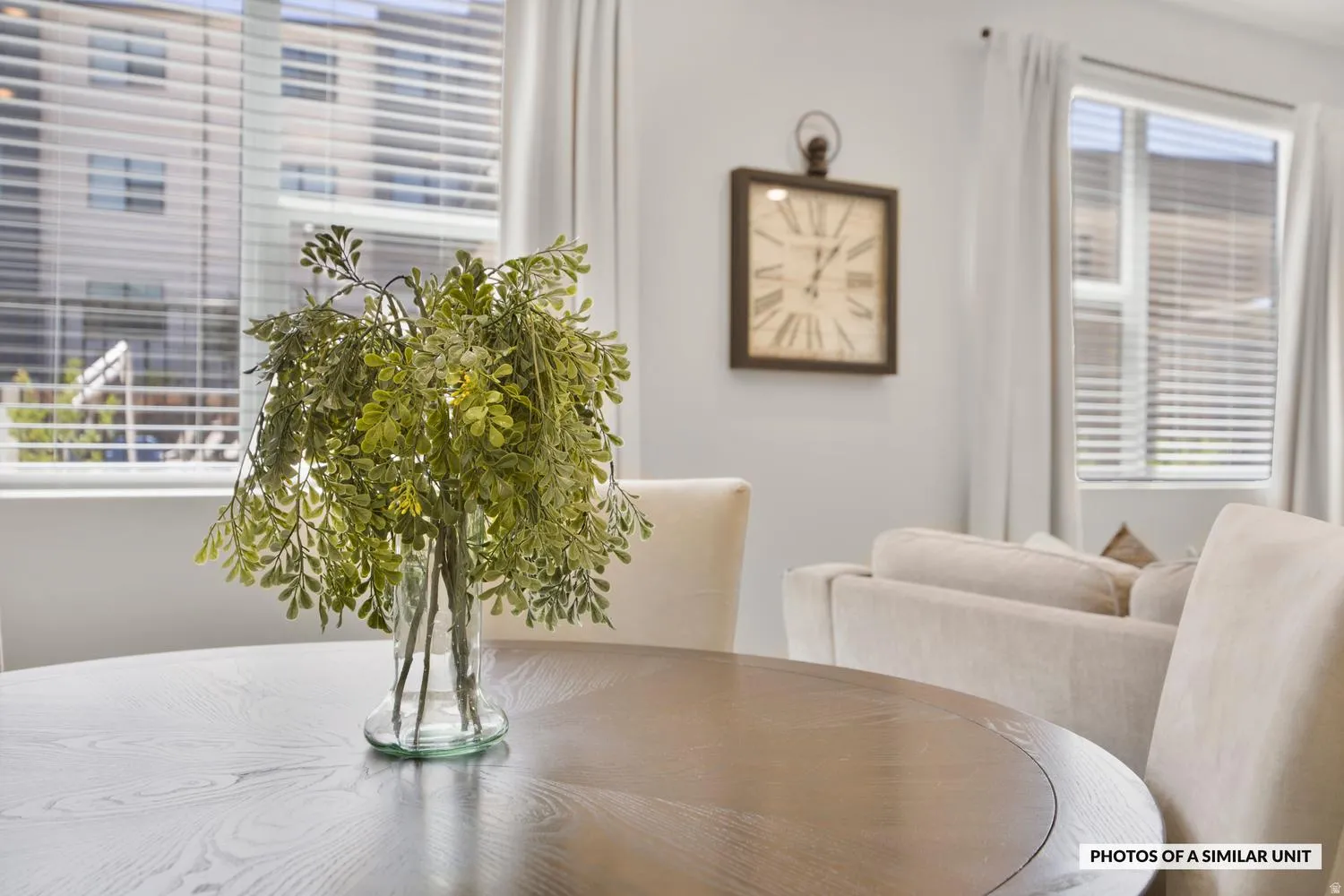 Dining area featuring a round wood-finish table, white walls, and multiple windows with horizontal blinds