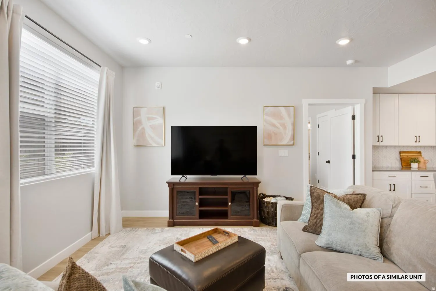 Open-concept living space featuring wood-finish flooring, recessed lighting, and a window with blinds and curtains