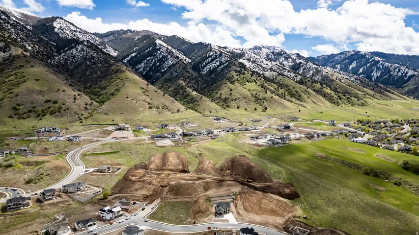 Expansive mountain landscape with partial snow caps and lush green slopes