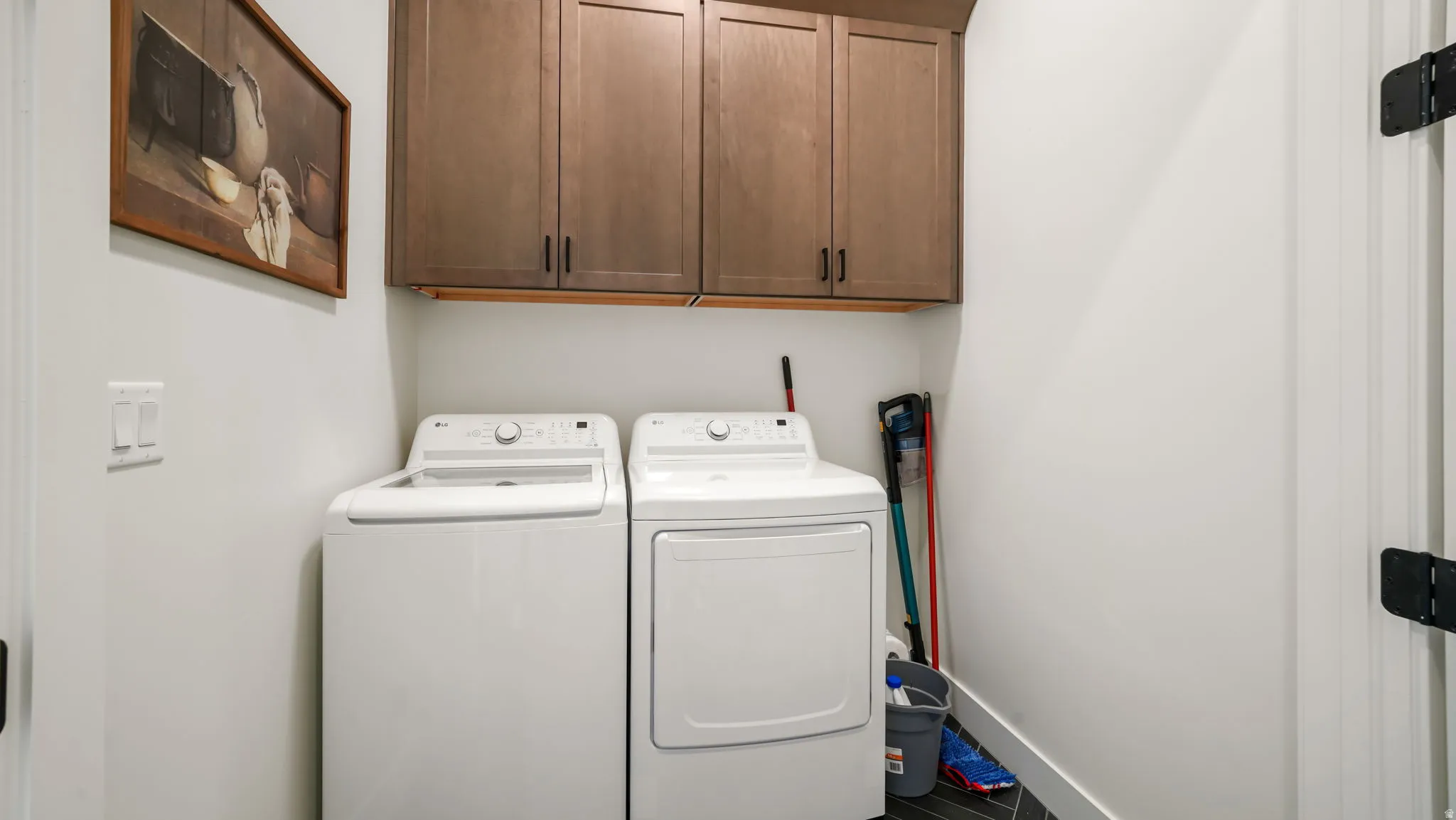 Dedicated laundry area featuring a washer and dryer, upper cabinetry with modern hardware, and dark wood-finish flooring