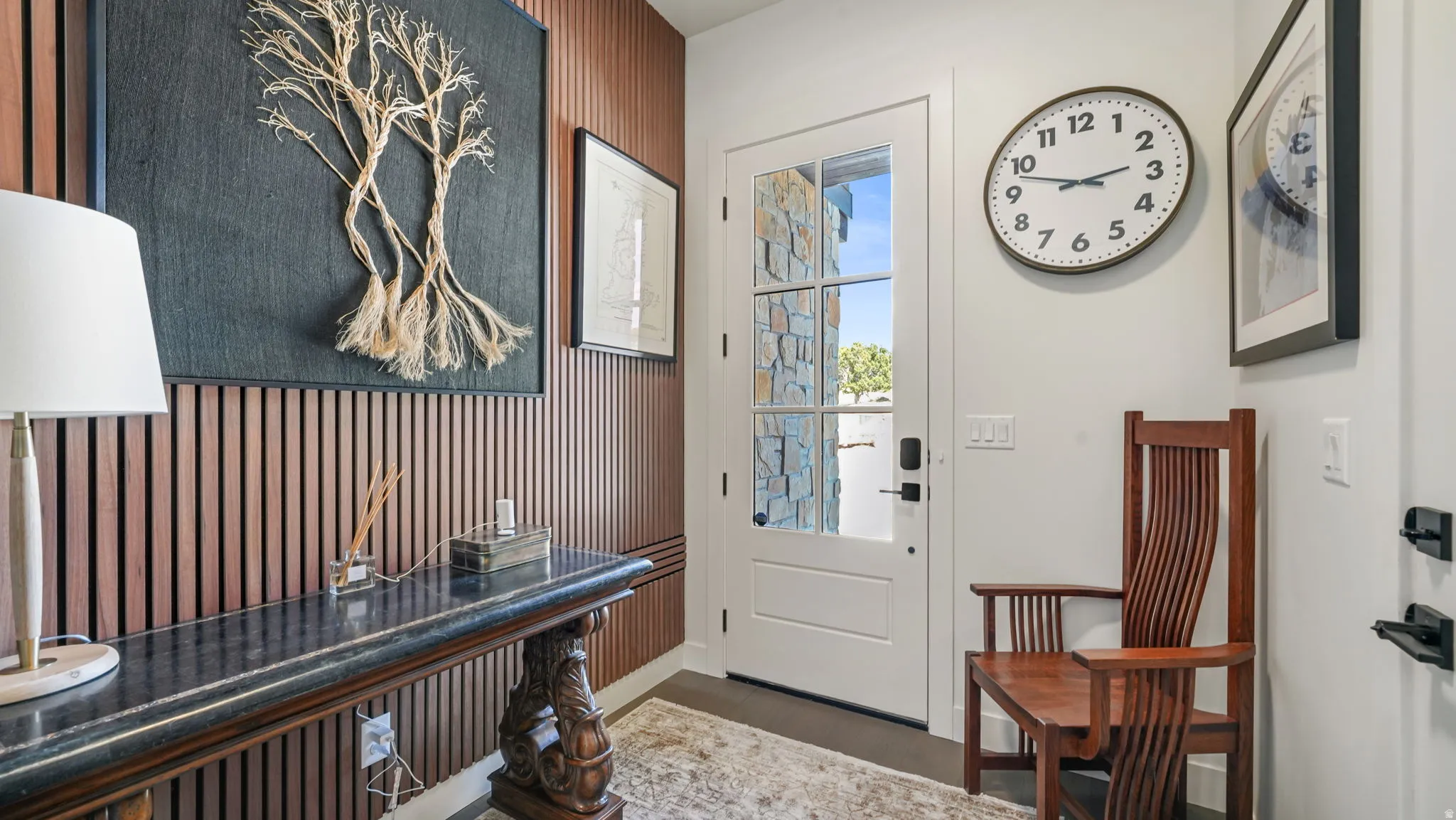 Entryway featuring a white paneled door with multi-pane glass, stone exterior accents visible through the door, and a decorative slatted wood accent wall