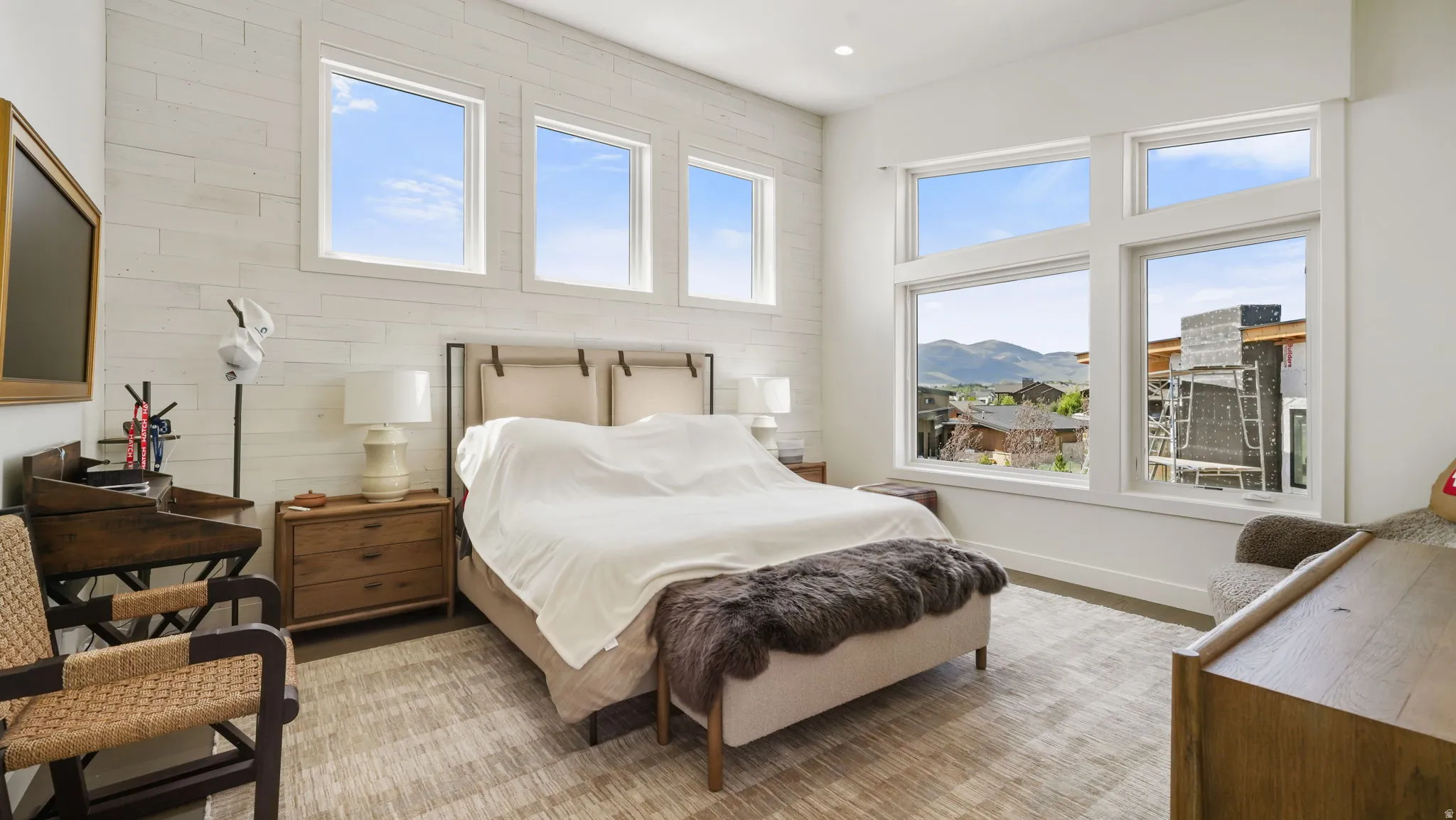 Spacious room featuring multiple large windows, shiplap accent wall, and a textured area rug
