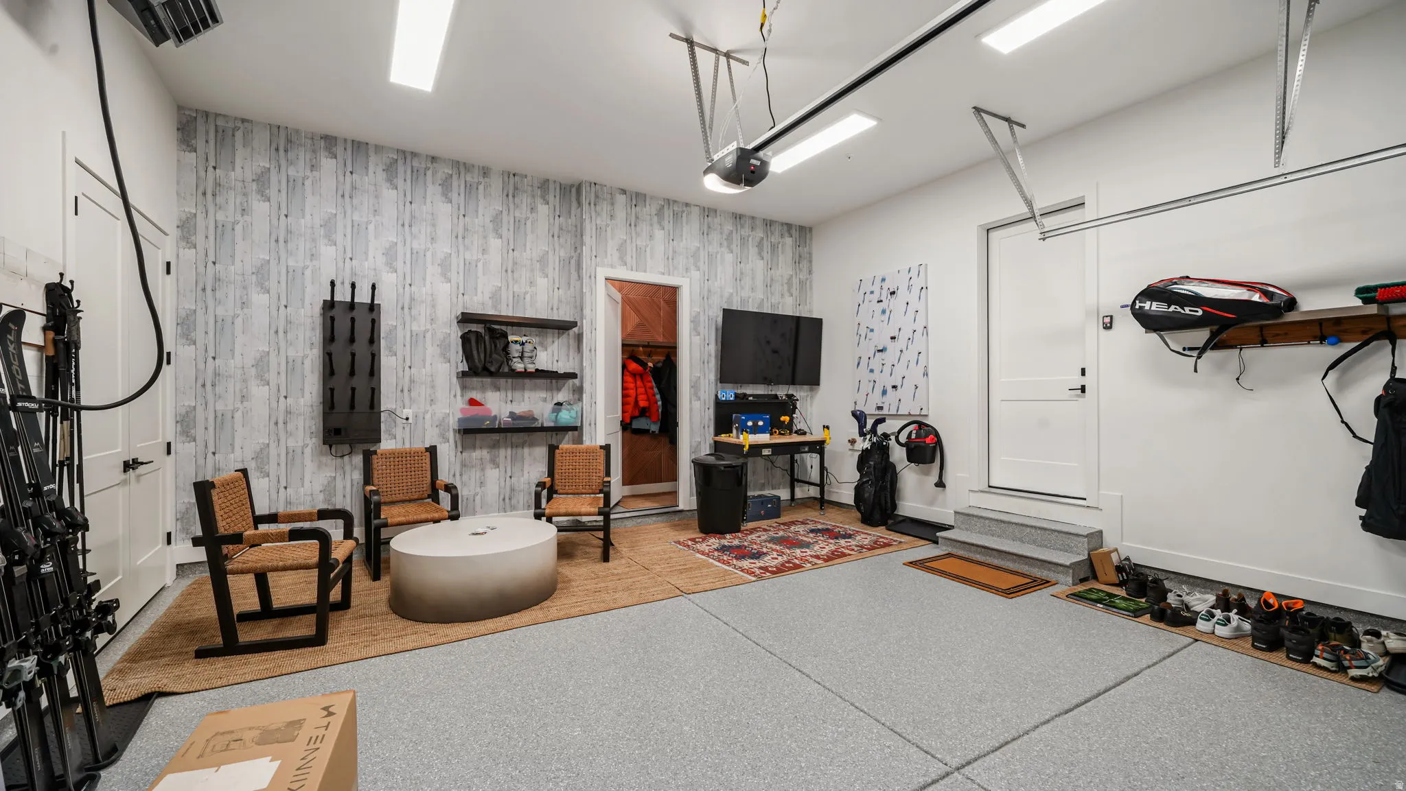 Spacious garage featuring a durable epoxy floor coating, recessed lighting, and a textured accent wall