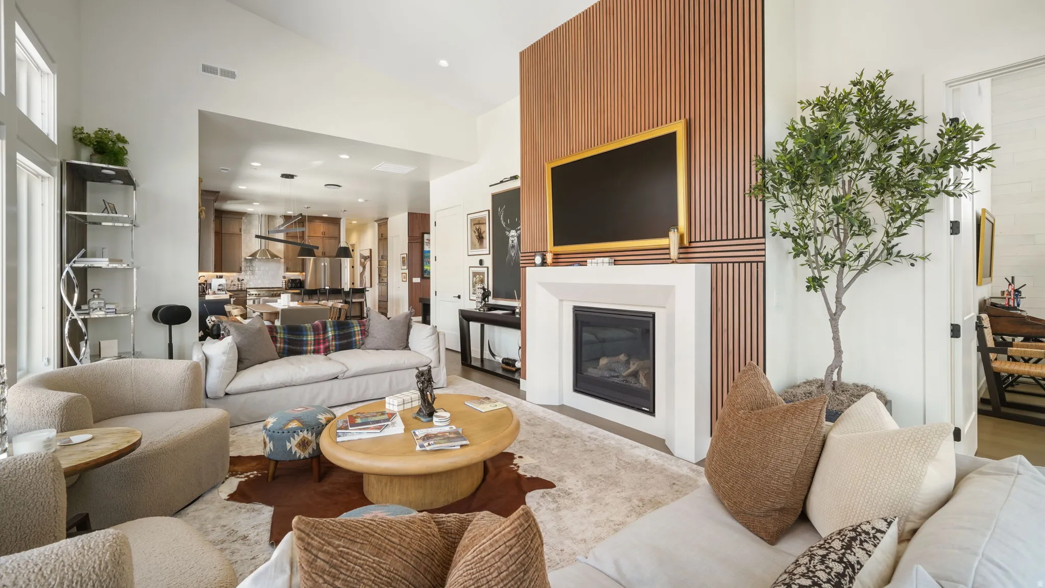 Living room featuring a gas fireplace with a white surround, a wood-slat accent wall, high ceilings, and recessed lighting
