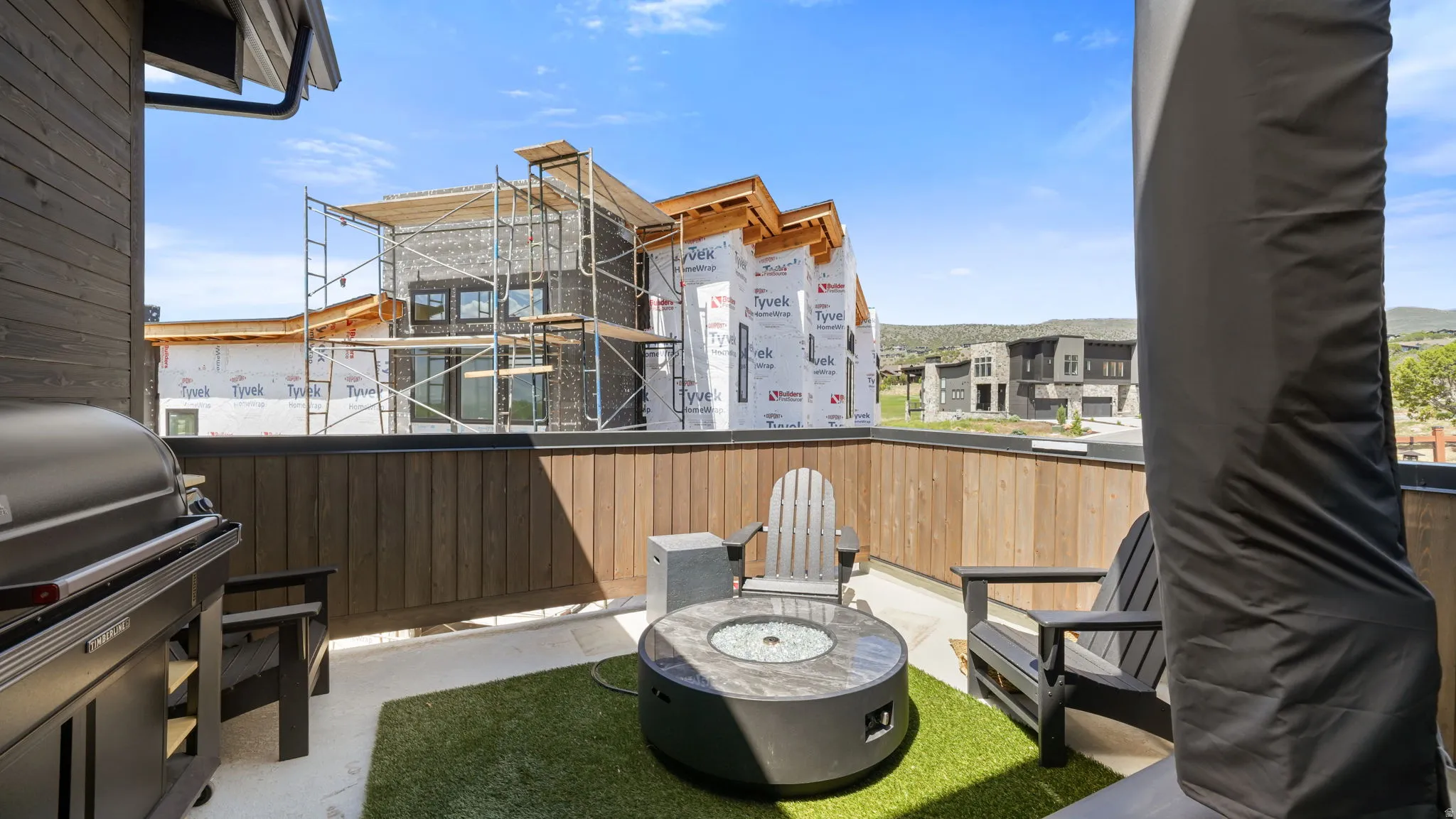 Outdoor patio featuring a built-in grill, a fire pit with a stone-finish top, and a wood-slat privacy wall
