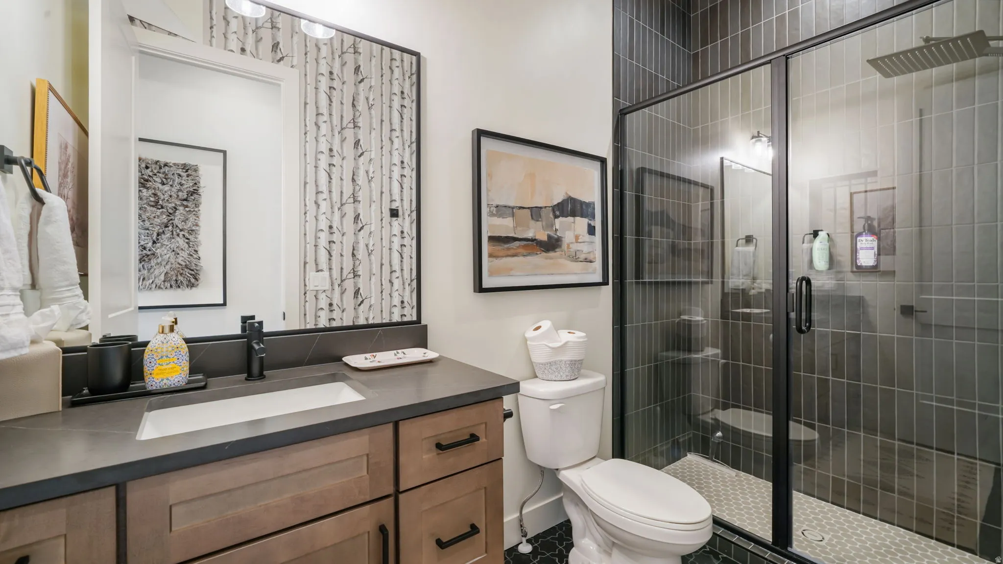 Modern bathroom featuring a glass-enclosed shower with vertical dark tile, a rain showerhead, and a white hexagonal floor tile