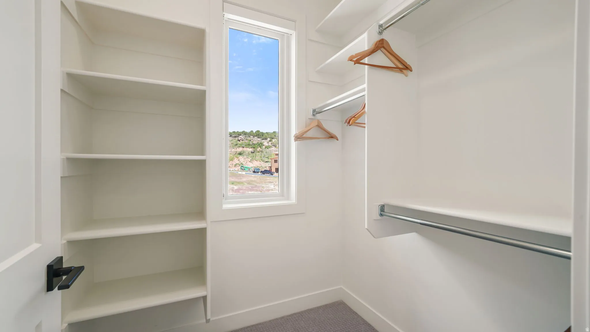 Walk-in closet featuring built-in shelving, multiple hanging rods, a window, and carpet flooring