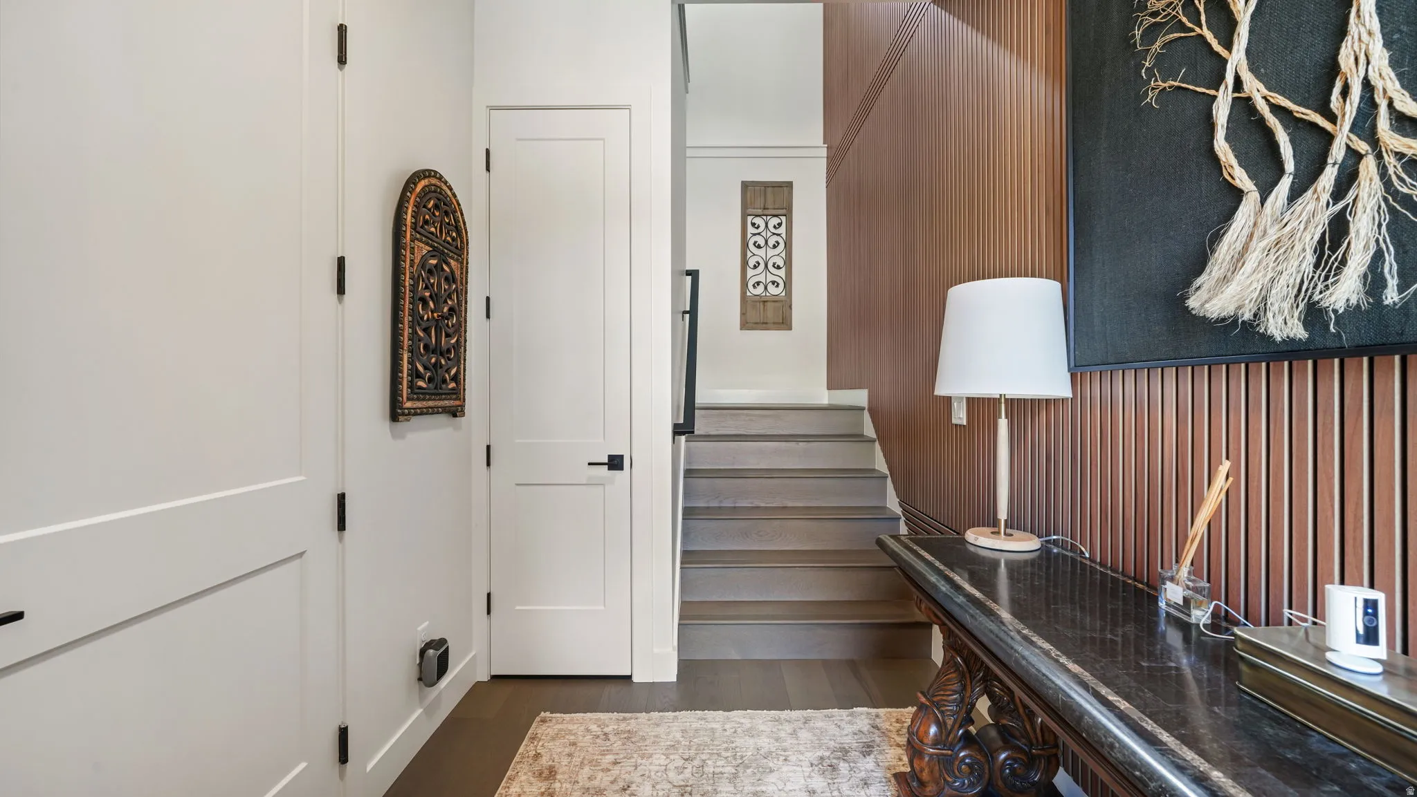 Entryway featuring a wood-panel accent wall, dark wood-finish flooring, and a staircase with dark risers
