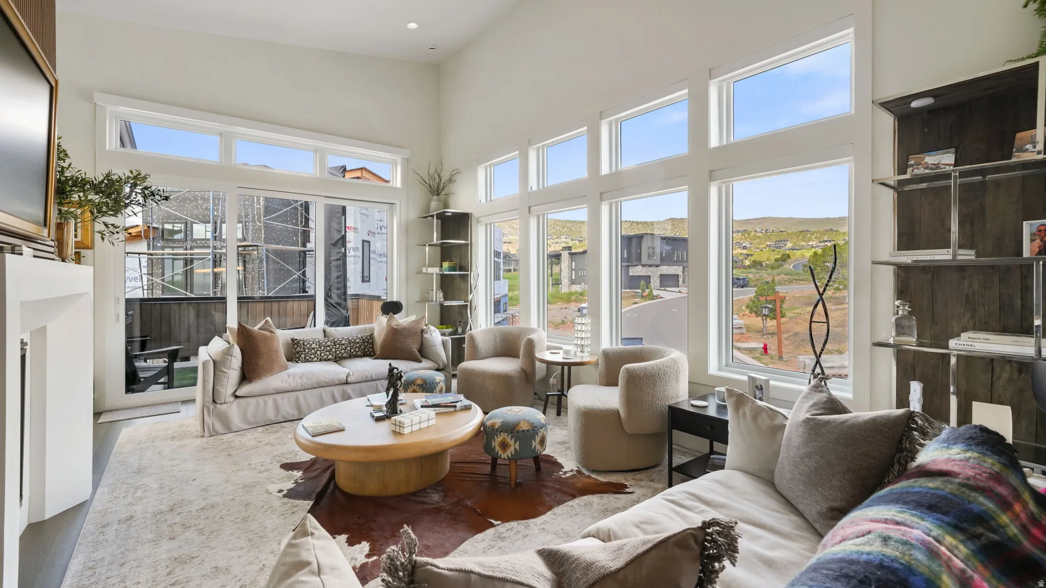 Living area featuring soaring ceilings, expansive windows, a sleek fireplace, and built-in shelving