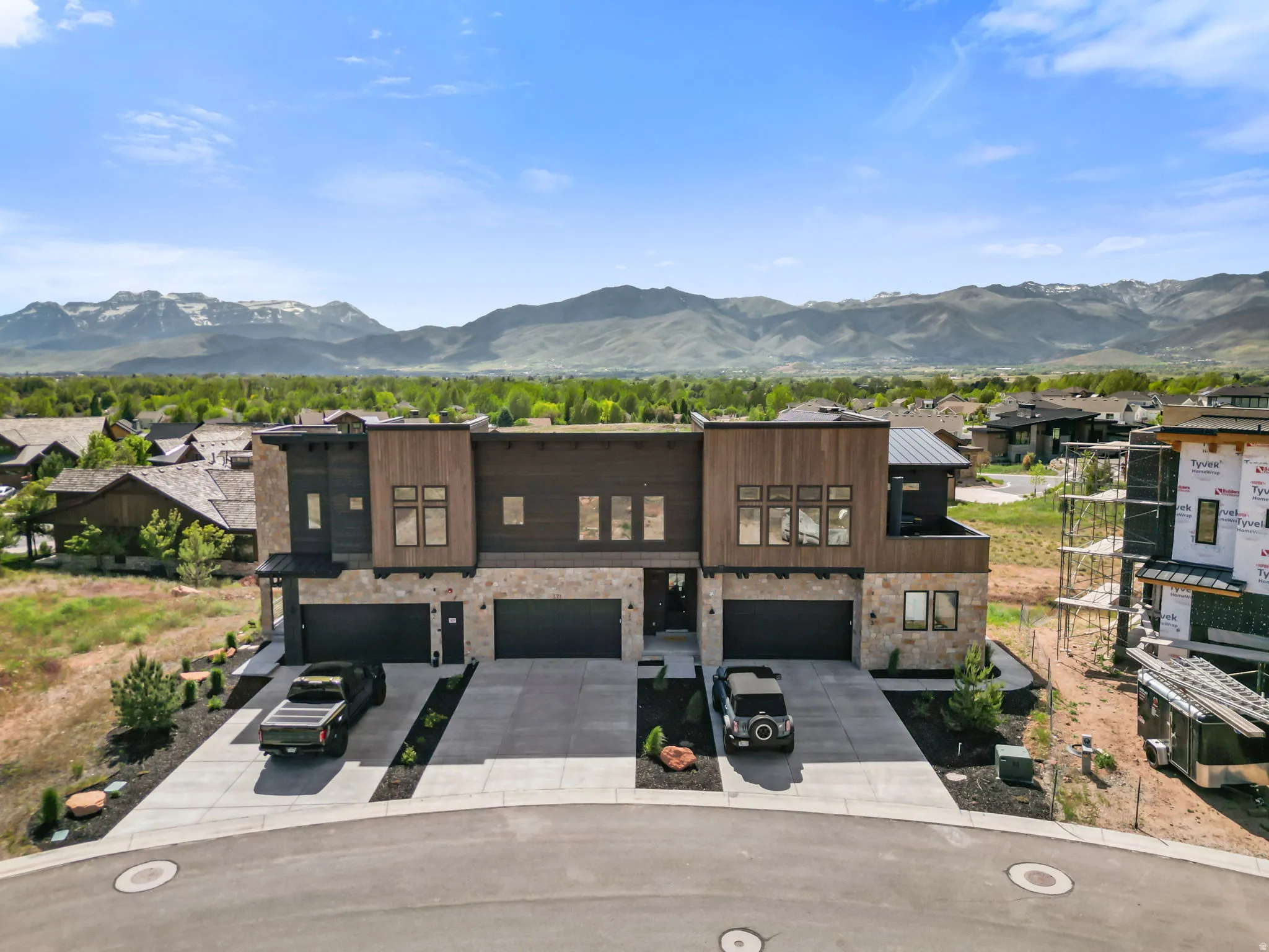 Modern townhome exteriors featuring wood-look siding, stone accents, and dark paneling