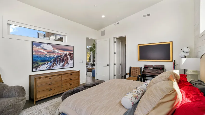 Bedroom featuring high ceilings, dark wood-finish flooring, and crisp white walls