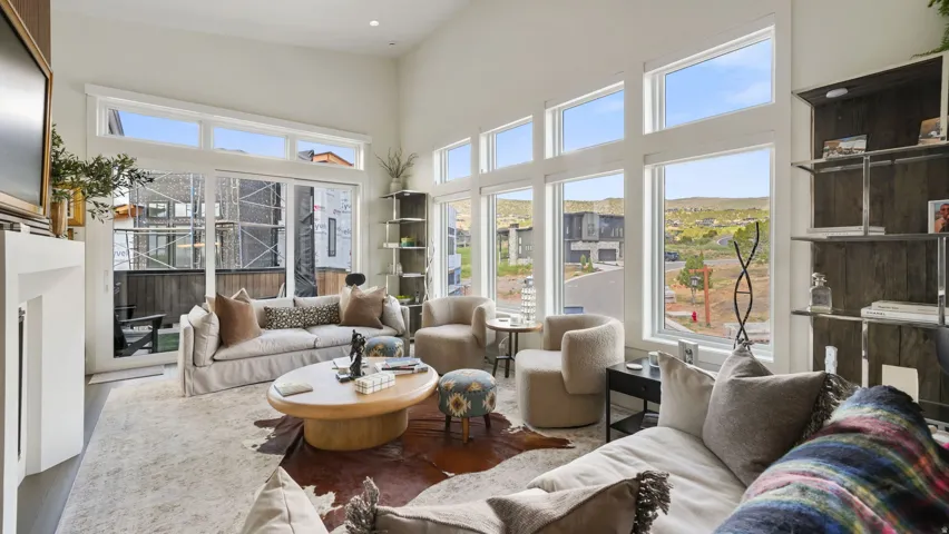 Spacious living area featuring high ceilings, extensive window walls, a built-in fireplace, and wood-finish flooring