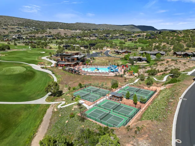 Aerial view showcasing multiple tennis courts, a swimming pool complex with water slides, a golf course, and a clubhouse