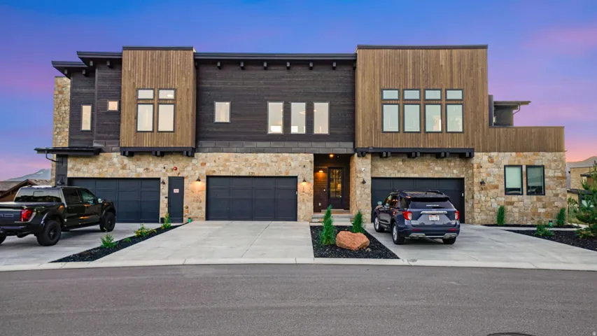 Modern facade featuring stone veneer, vertical wood siding, and dark horizontal paneling
