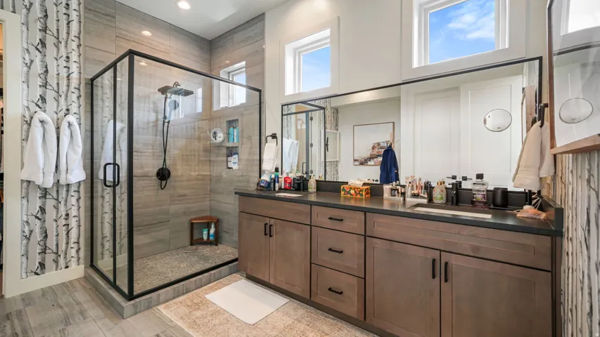 Spacious bathroom featuring a glass-enclosed shower with pebble flooring and tiled walls