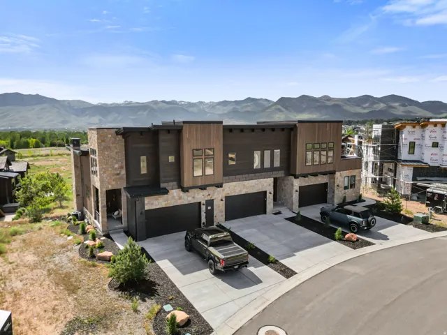 Contemporary multi-unit residence featuring stone and wood-finish siding with dark trim accents