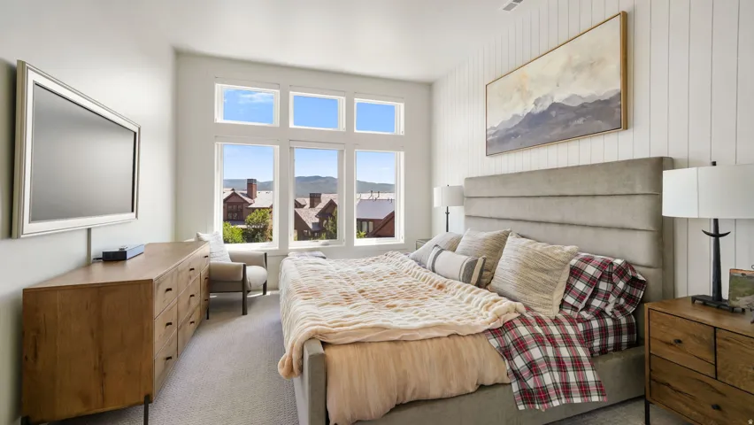 Carpeted bedroom featuring a shiplap accent wall, a multi-pane window configuration, and a built-in window seat