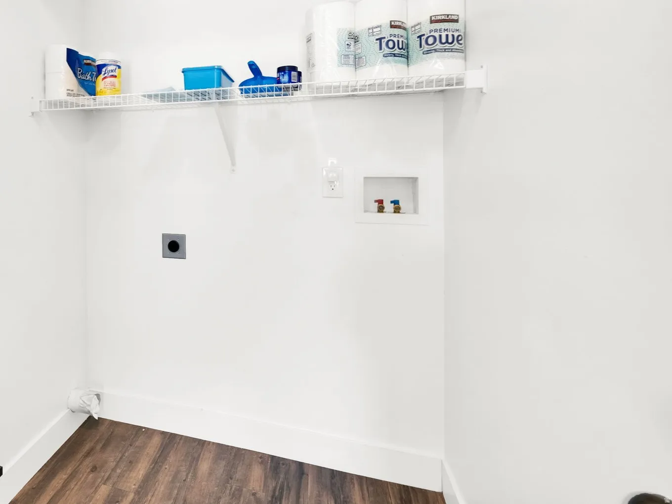 Dedicated laundry space featuring wood-finish flooring, white walls, and bright overhead lighting