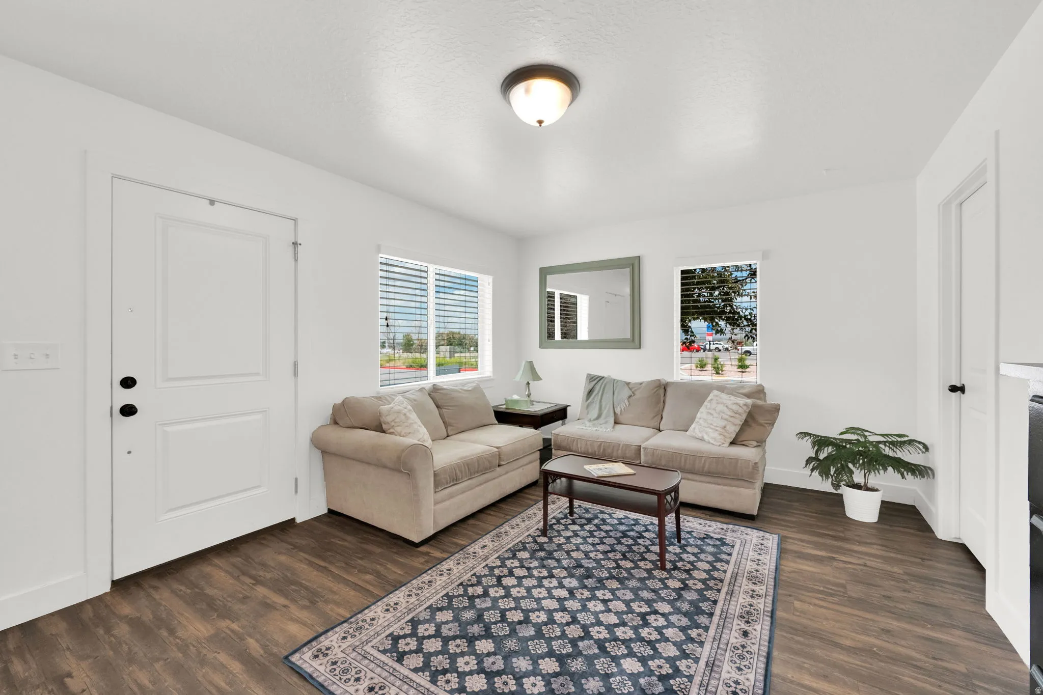 Living area featuring wood-finish flooring, white walls, and a ceiling-mounted light fixture
