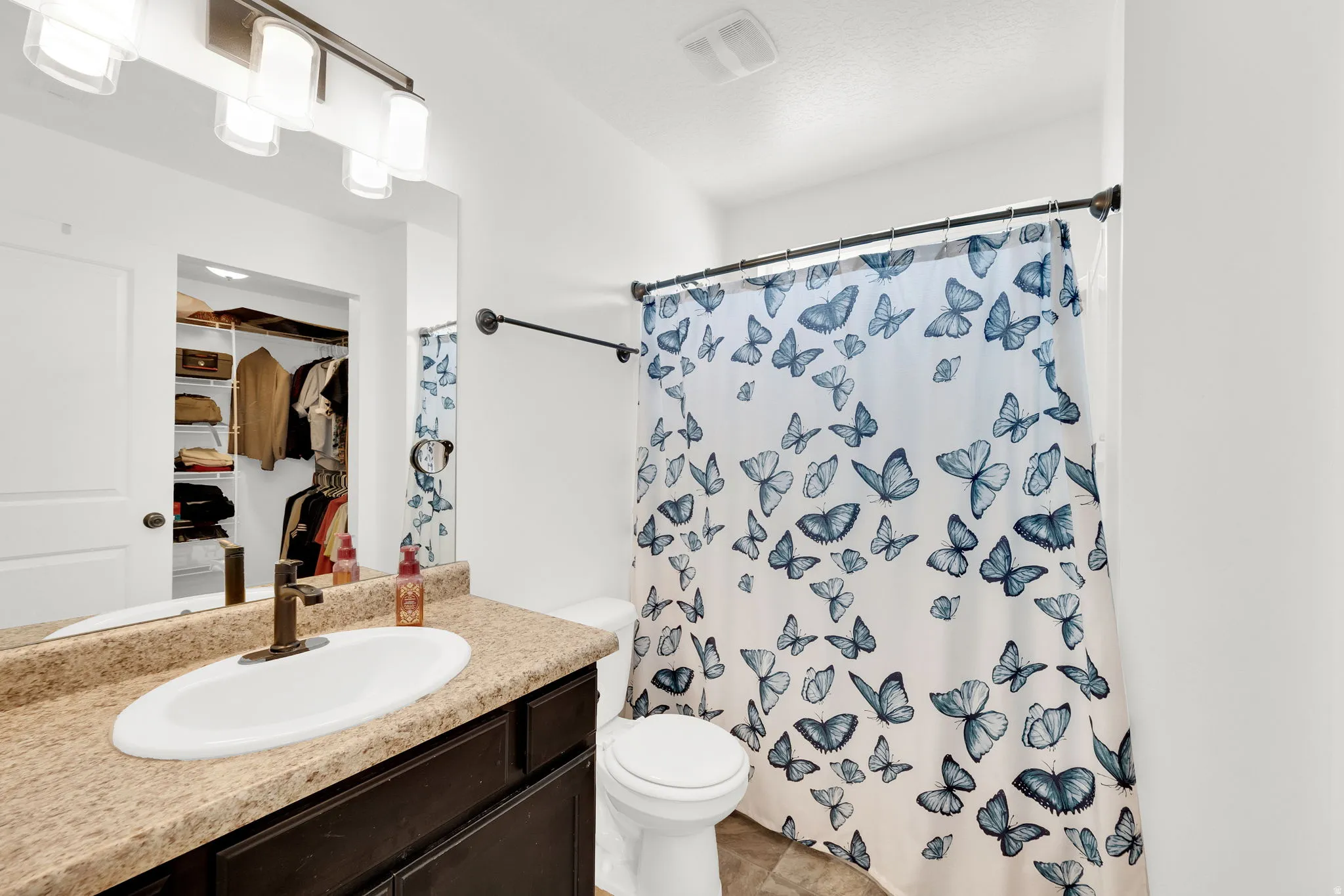 Bathroom featuring a single vanity with a laminate countertop, undermount sink, and a bronze-finish faucet