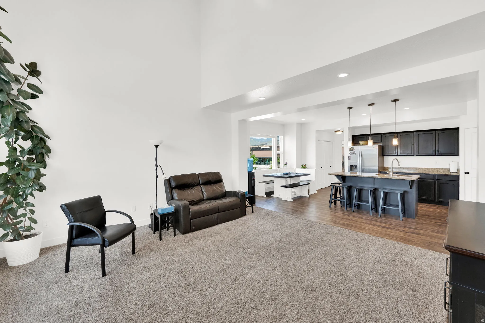 Open-concept living space featuring high ceilings and a blend of carpet and wood-finish flooring