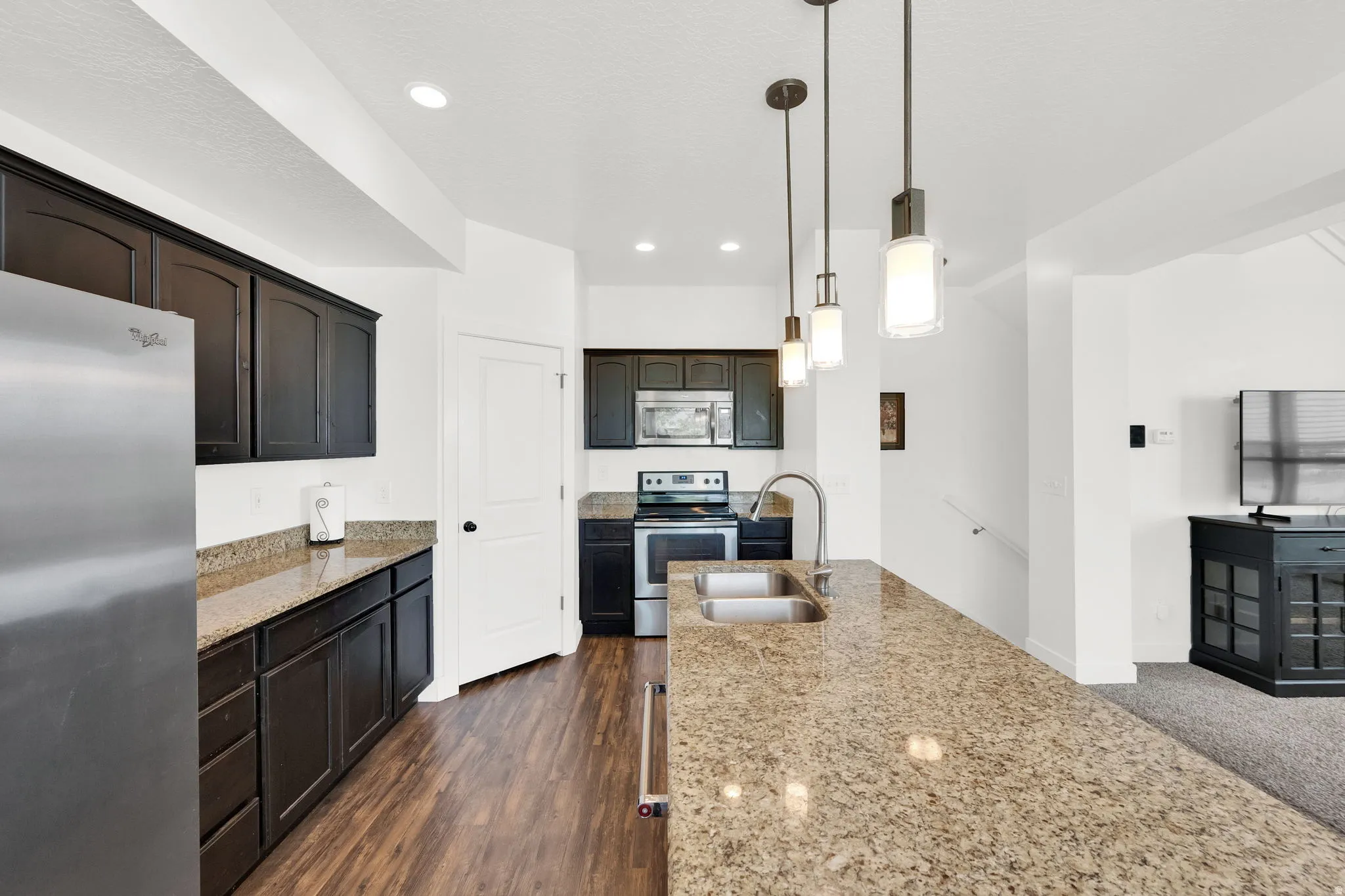 Kitchen featuring dark wood-finish cabinetry, stainless steel appliances, granite countertops, and wood-finish flooring