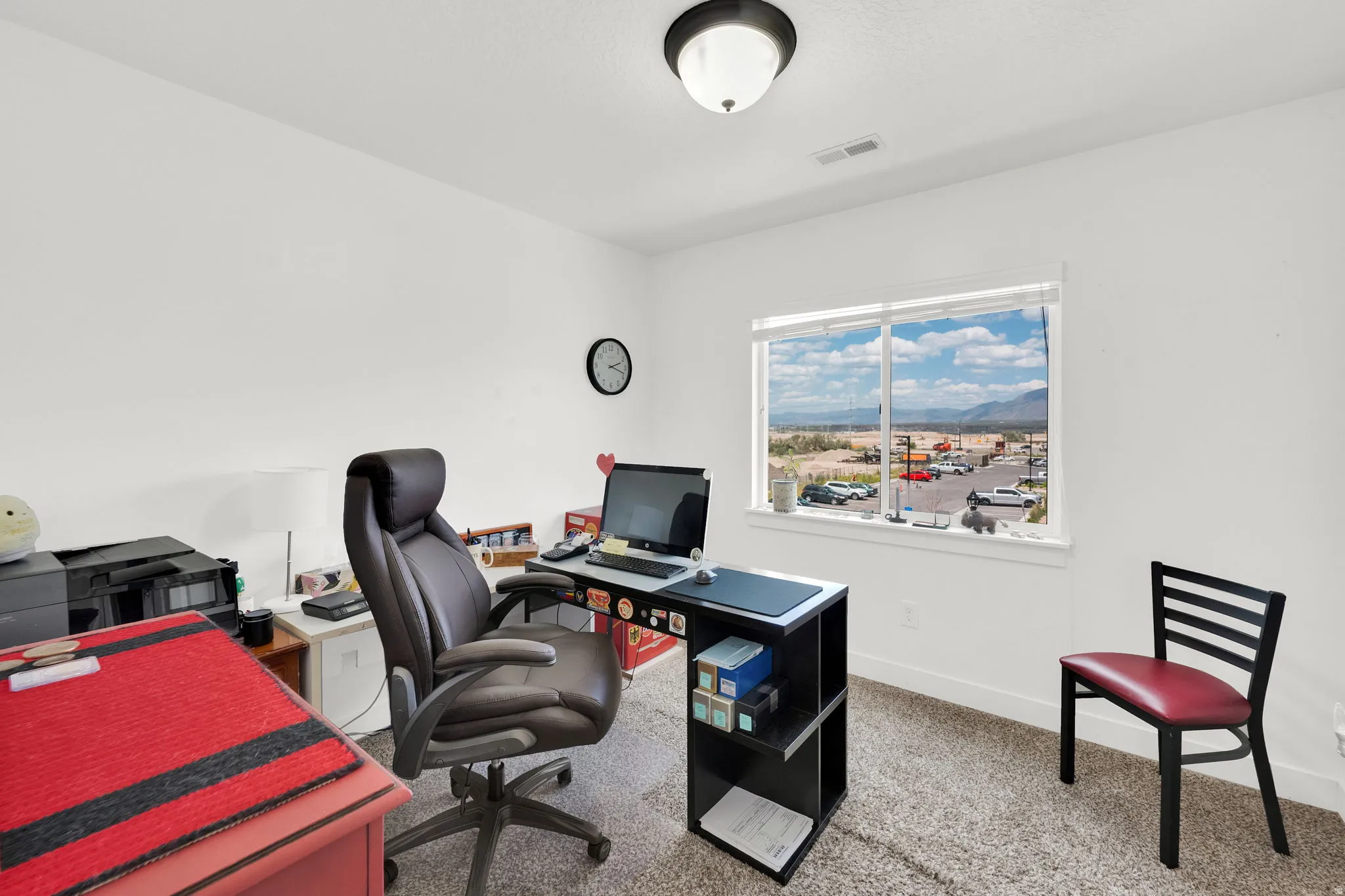 Bright room featuring a large window, white walls, and neutral-toned carpeting