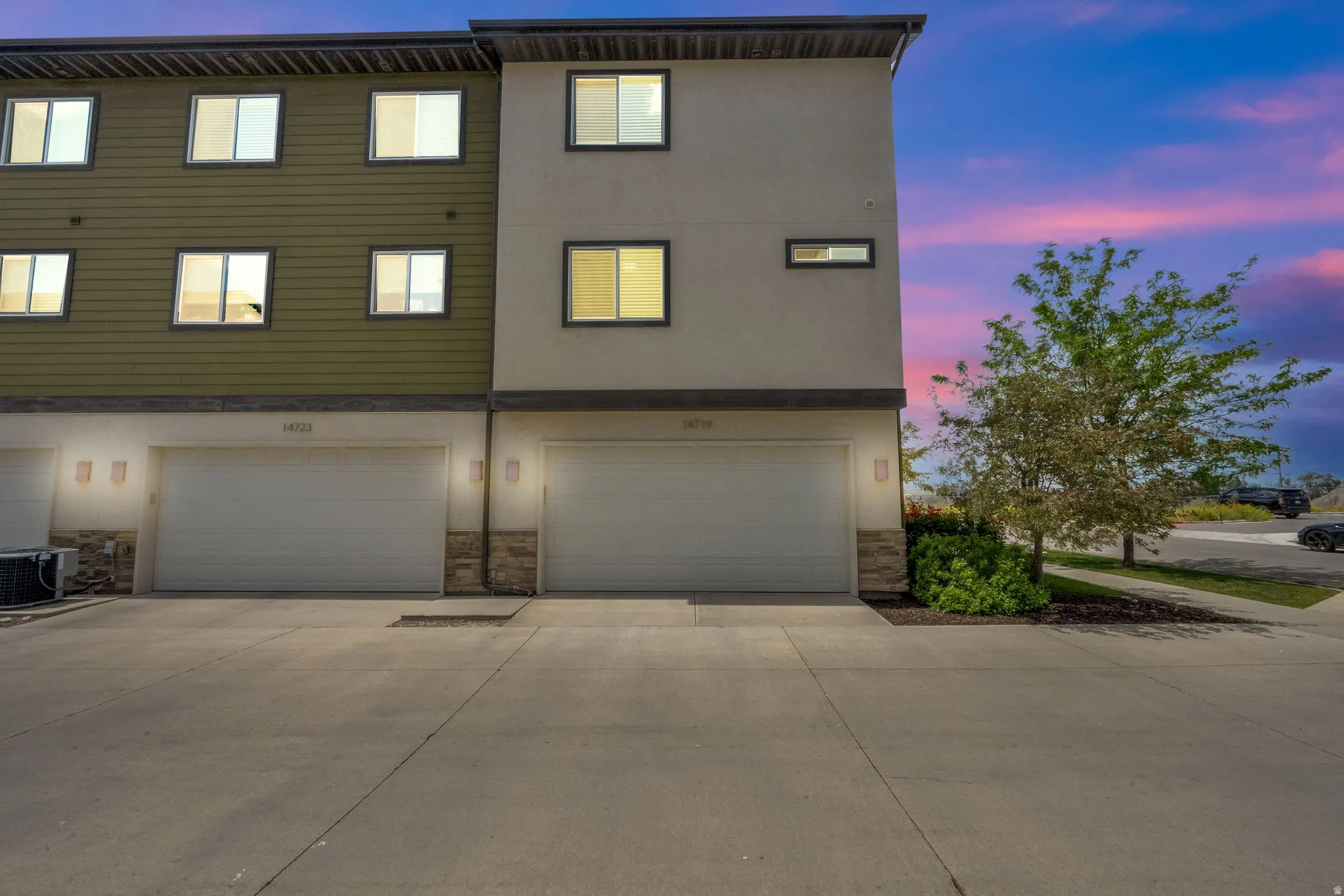 Contemporary townhome exterior featuring a neutral stucco facade and olive green horizontal siding