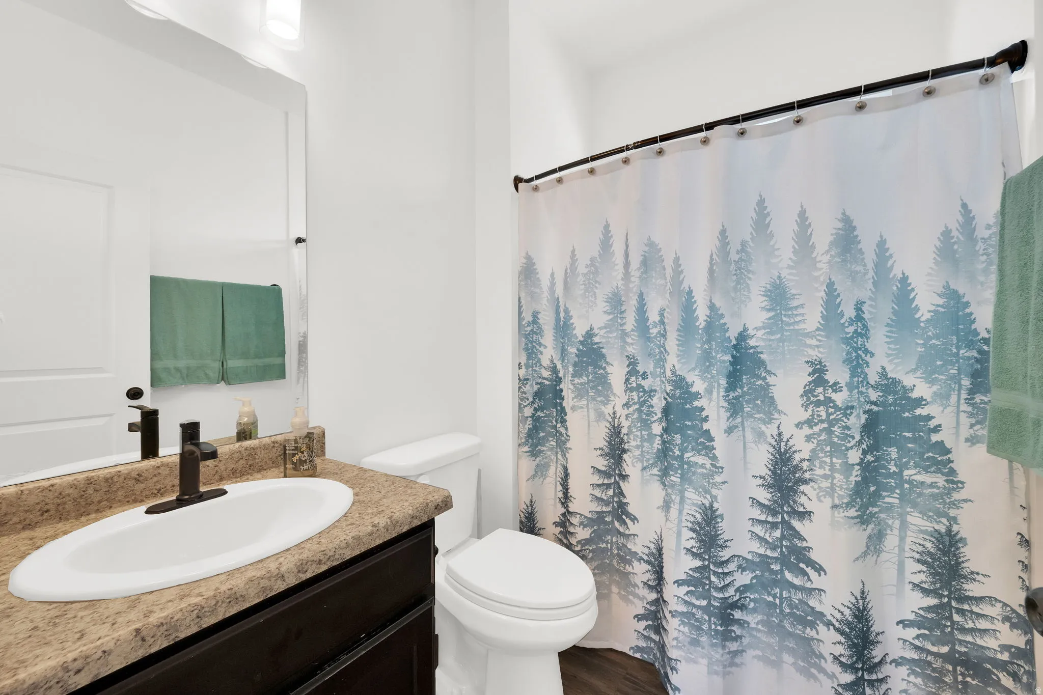 Bathroom featuring a vanity with a dark wood-finish cabinet, a speckled countertop, and a white oval under-mount sink with a matte black faucet