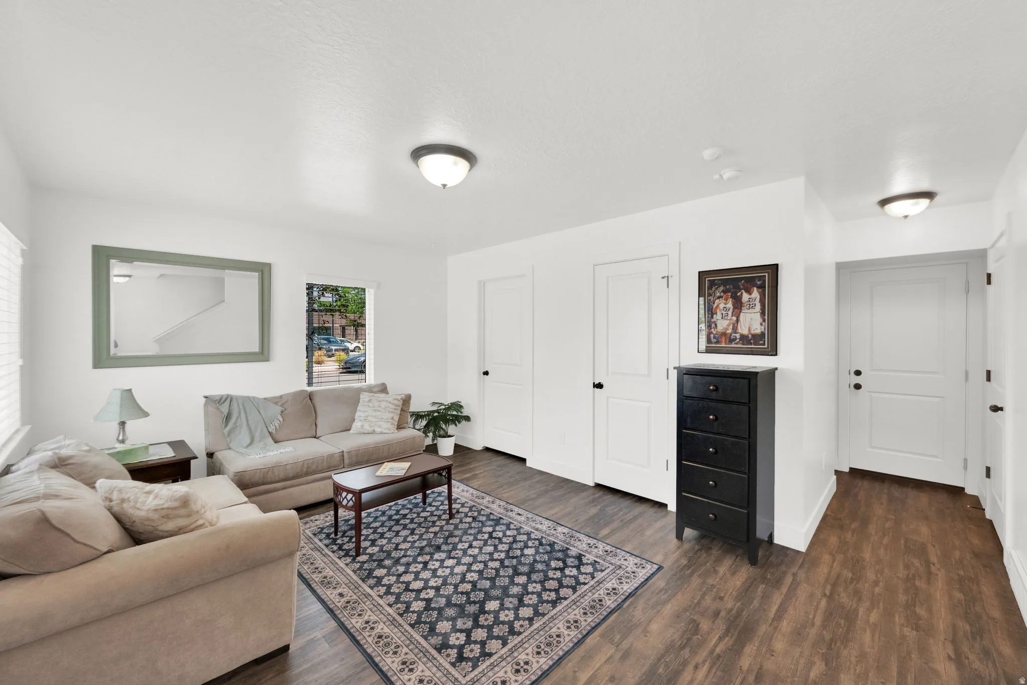 Living area featuring wood-finish flooring, white walls, and multiple panel doors