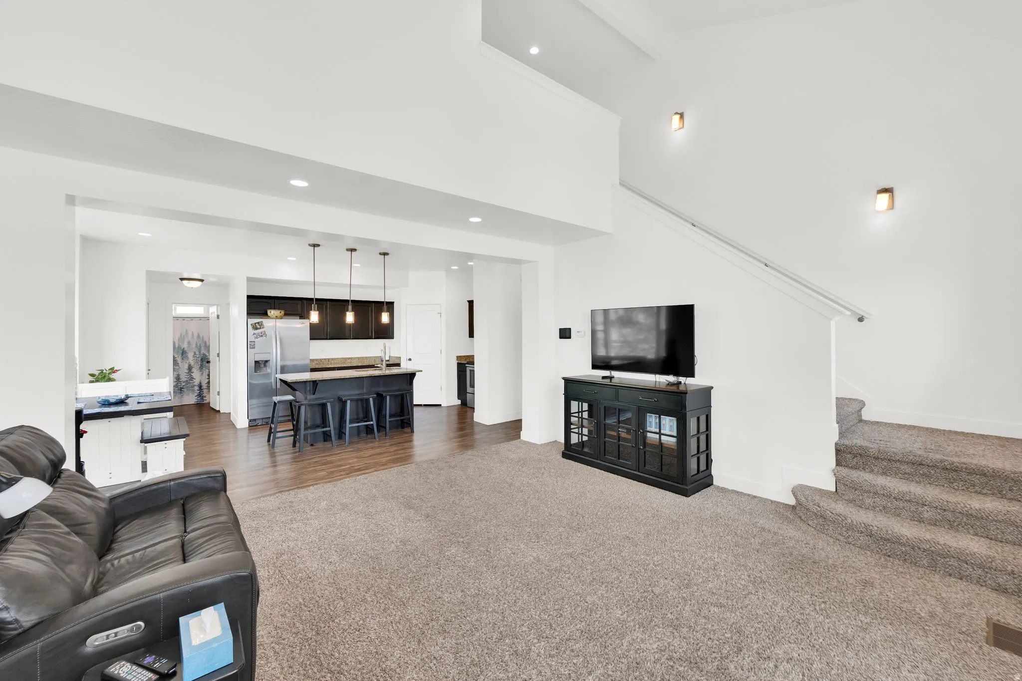 Open-concept living space featuring a high ceiling, recessed lighting, and a neutral color palette