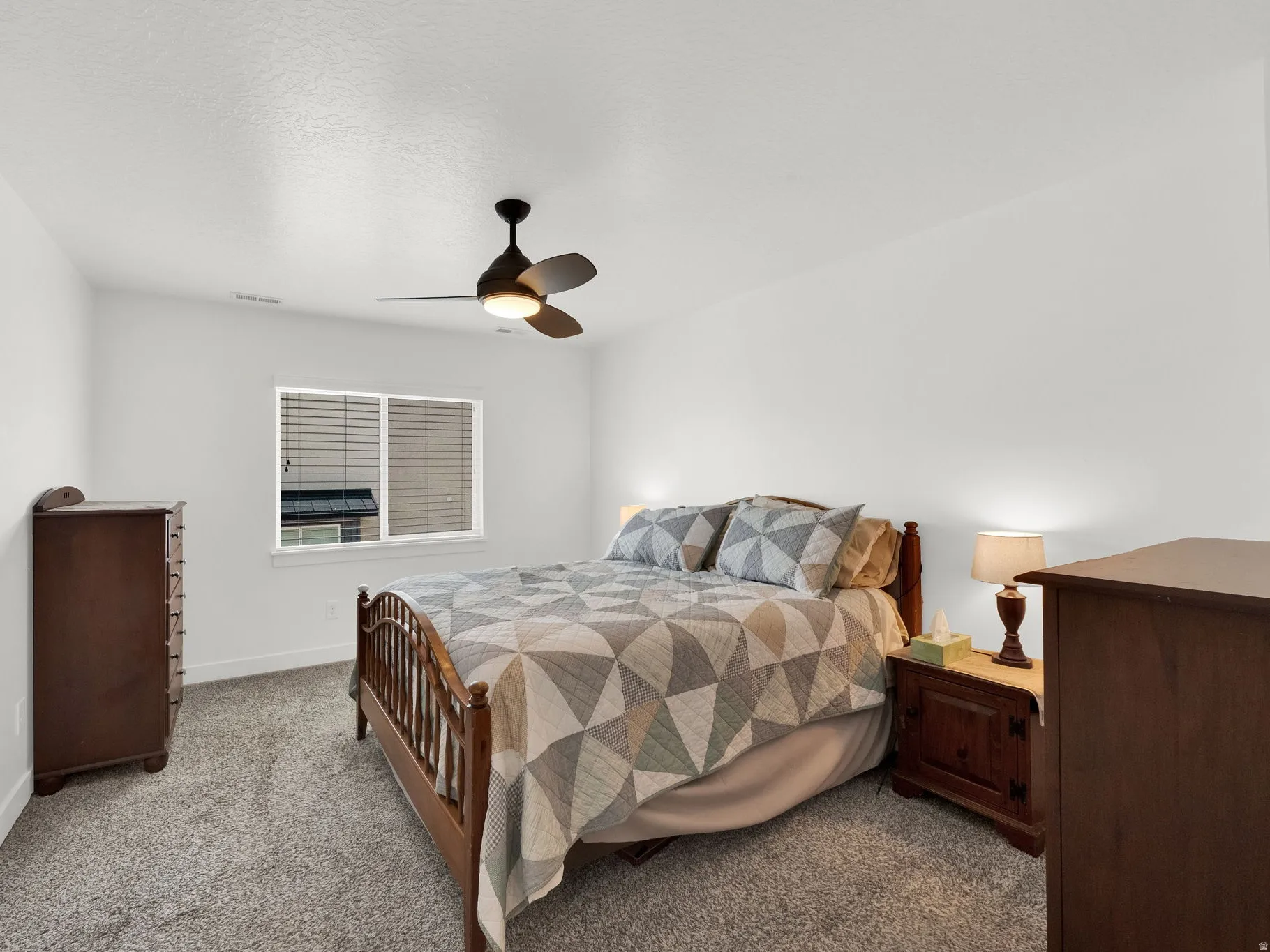 Bedroom featuring neutral wall colors, textured carpeting, a window with horizontal blinds, and a ceiling fan with integrated lighting