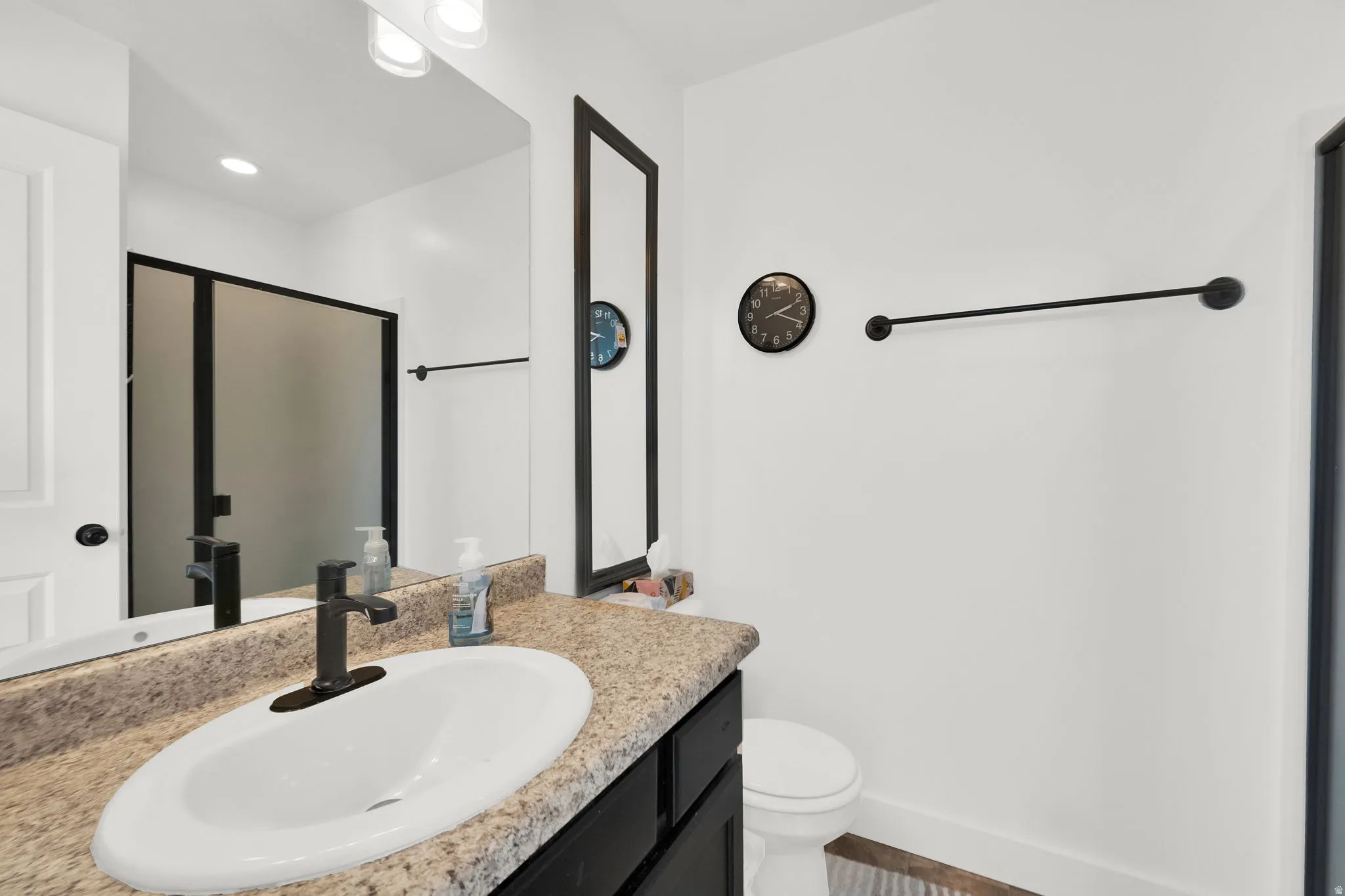 Bathroom vanity featuring a white oval sink with a matte black faucet set against a speckled countertop