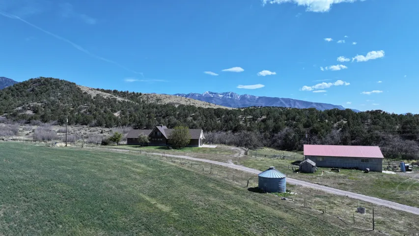 Expansive rural property featuring a main residence, a large barn with a red roof, a separate outbuilding, a grain silo, and a gravel driveway